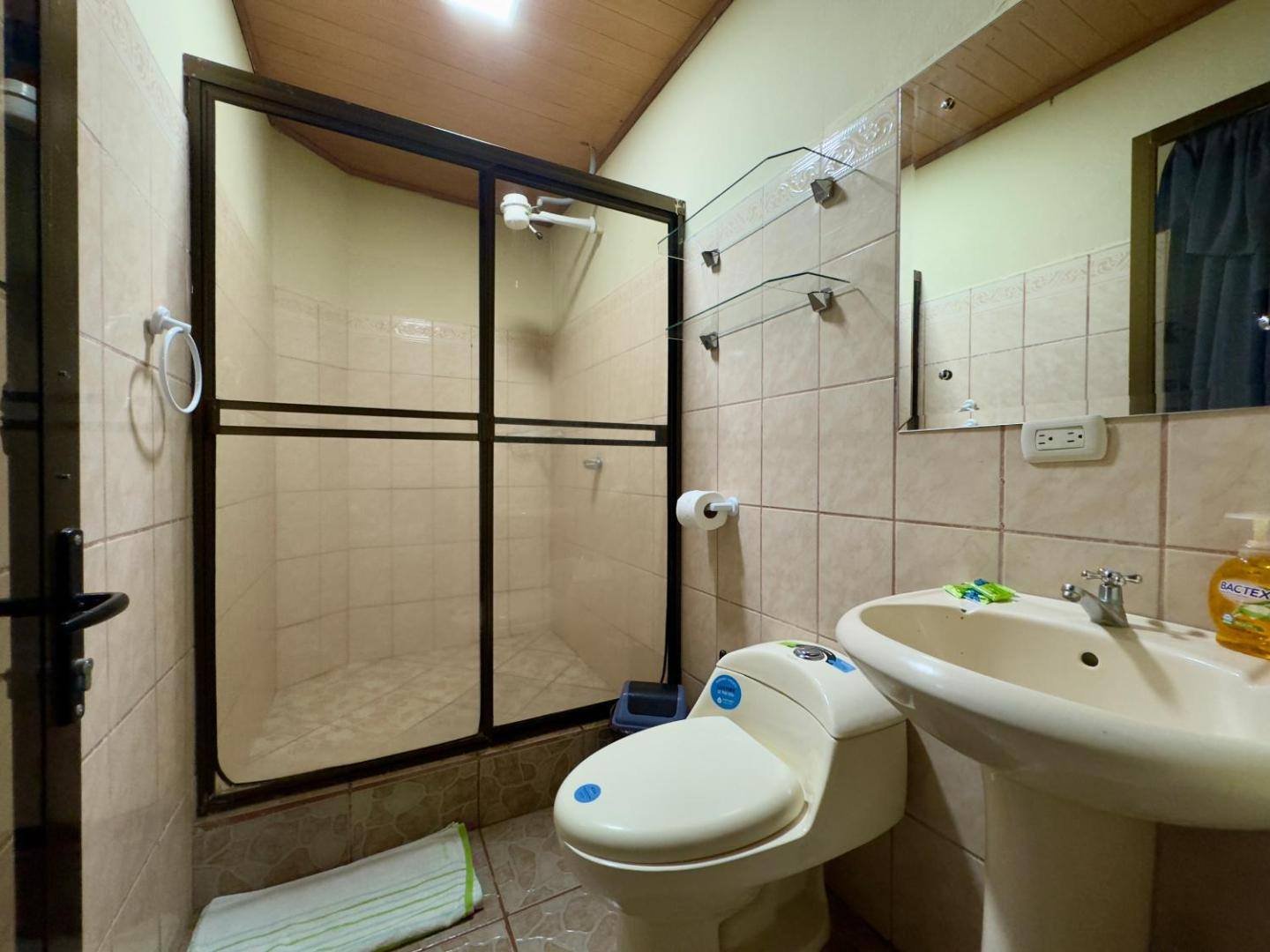 A private bathroom with a glass shower door, a pedestal sink and a toilet